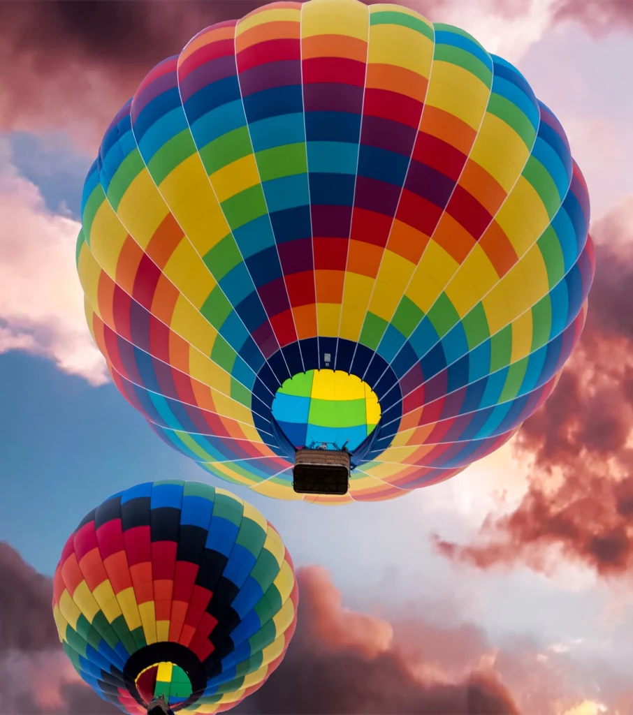 2 colorful balloons float up into the sunrise