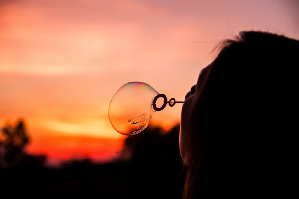 woman blowing bubbles at sunset