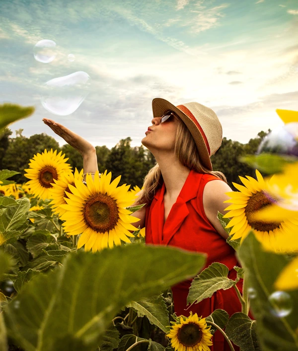 woman blowing bubbles in a sunflower field in fall