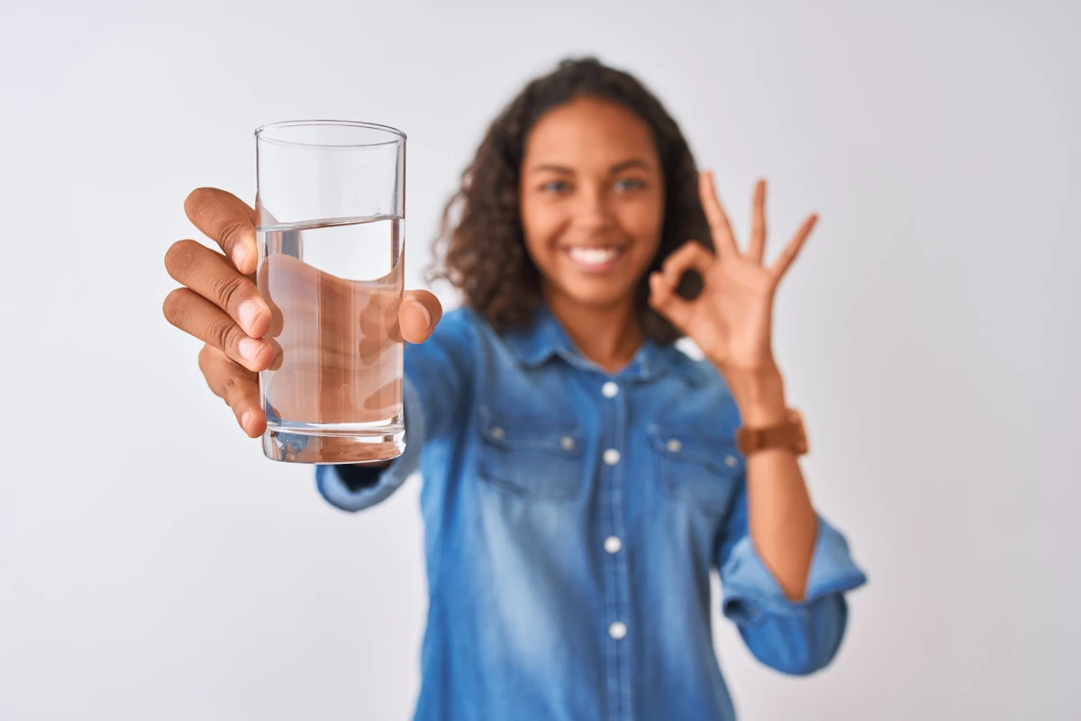 woman with glass of water and okay sign why hydration matters